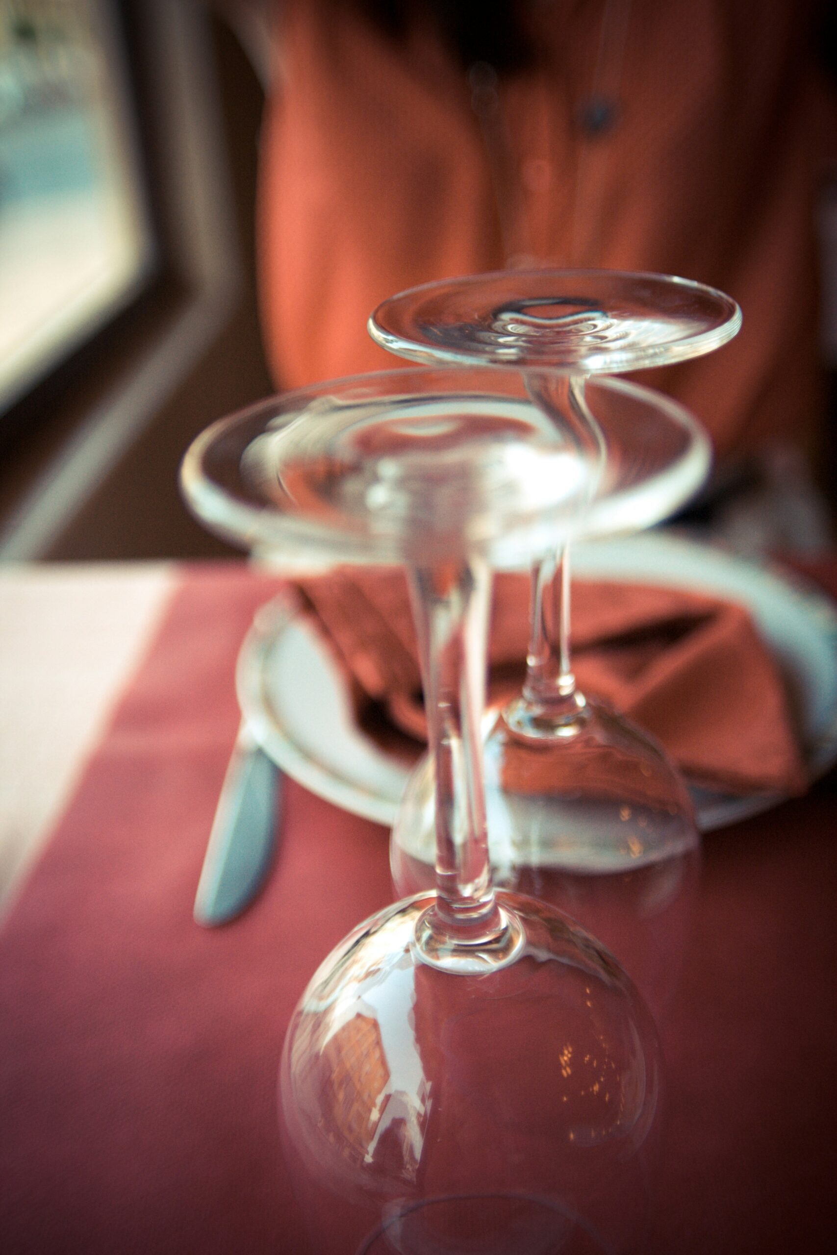 Photo of upside down wine glasses on a red cloth napkin ready to be used.