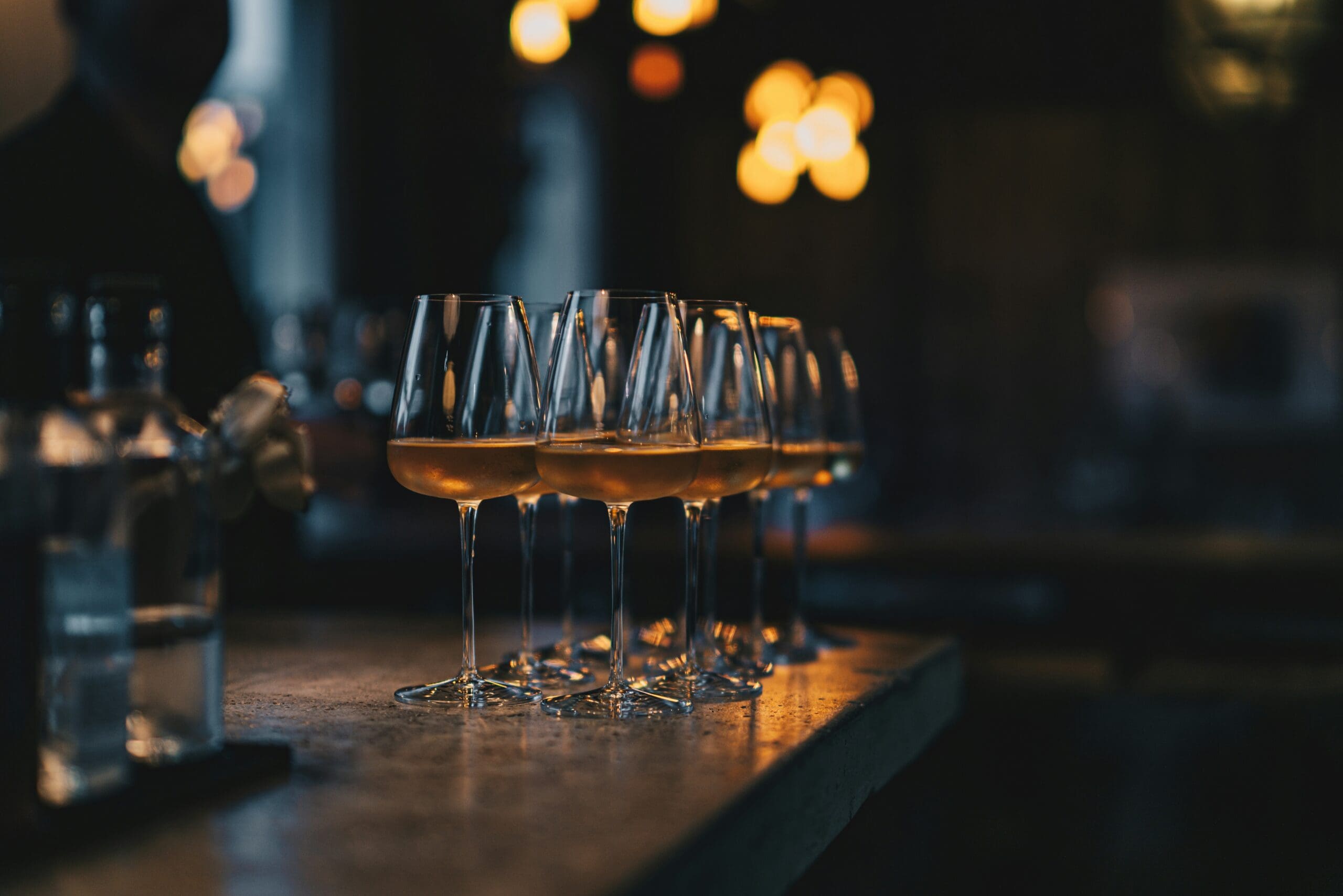 White wine glasses lined up on the bar for a country club wine tasting
